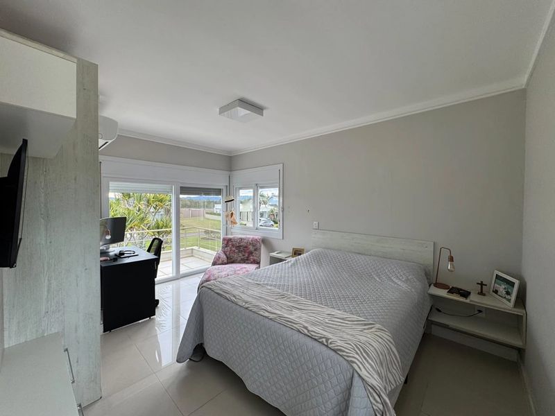 Dormitório com cama de casal, mesa de trabalho, ar-condicionado e acesso à sacada