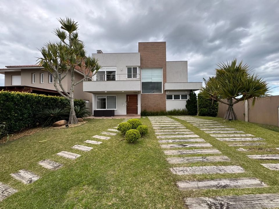 Fachada do sobrado de esquina, com jardim gramado e passadiço de madeira até a entrada