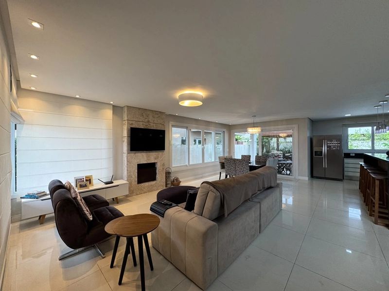 Sala de estar com lareira e televisão, vista em ângulo amplo até a área gourmet