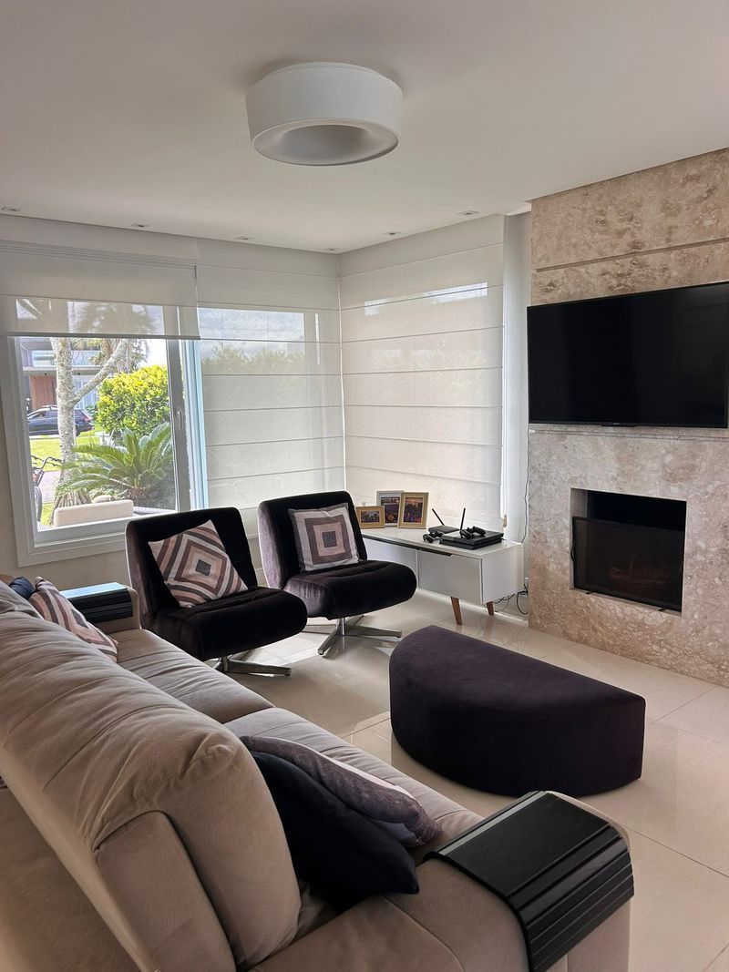 Sala de estar com sofá, poltronas, televisão e lareira em revestimento de pedra